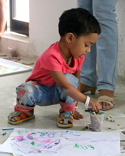 small child squatting on the floor drawing with crayons