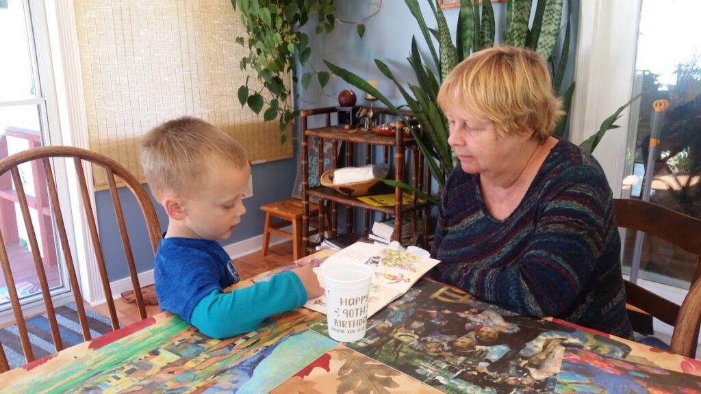 boy and older woman reading together at a table